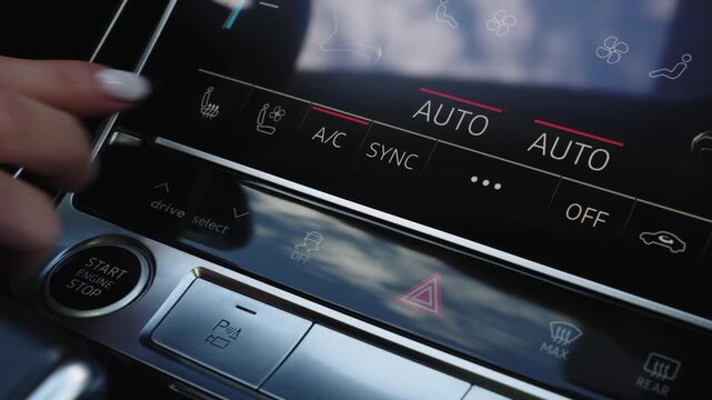 Close-up of female hand pressing AC button on digital touchscreen climate control panel in modern car. Dark sleek vehicle dashboard display with active glowing auto indicators and sync option.