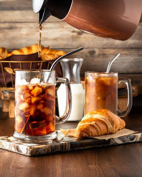 Glasses of iced coffee with coffee being poured into one of the glasses.