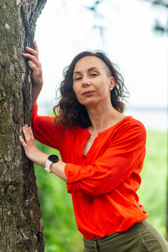Woman Leaning on Tree in Bright Red Blouse