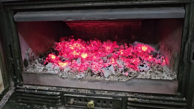 Glowing Fireplace Coals and Ash Burning Inside Wood Stove With Red Embers and Heat From Indoor Fire