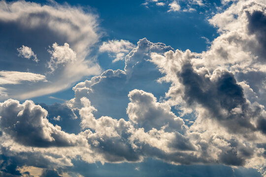 Dynamic blue sky filled with dramatic cumulus clouds. Beautiful sky background with fluffy white and dark cumulus clouds contrasting against bright blue backdrop on sunny day