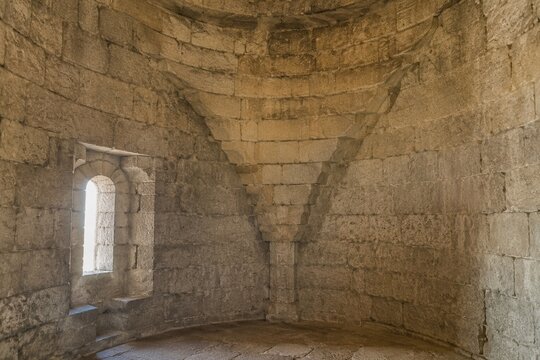 Interior of a round stone tower, corner where masonry walls curve inward to support the ceiling.