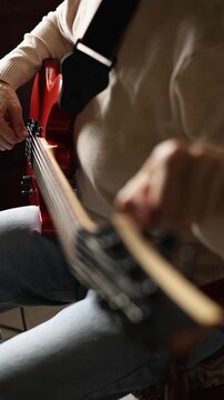 Close up view of woman's hands tuning strings on headstock of electric guitar indoors. Concept of musician preparing for performance, practicing song, musical instrument setup and hobby.