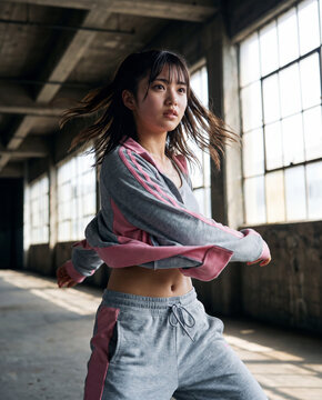 コンクリート打ちっ放しのスタジオで躍動的に踊る若い女性ダンサー