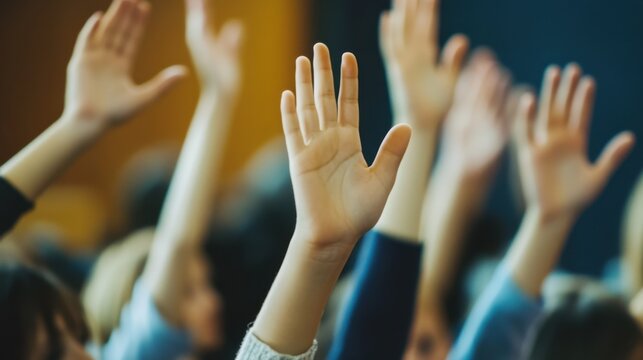 Close up of children raising their hands in a classroom during a lesson. Education and teamwork concept