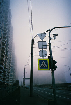 Traffic signs and power lines frame a foggy urban highway at dusk