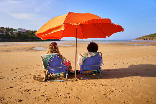 Couple relaxing on beach chairs under umbrella