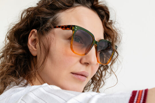 Portrait of a woman with curly hair wearing sunglasses.