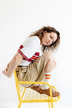 A woman is sitting on a yellow chair.