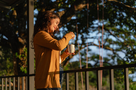 Woman smiling preparing tea relaxing outdoors at golden hour