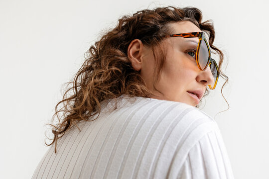 Portrait of a woman with curly hair wearing sunglasses.