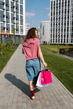 A woman walks with shopping between high-rise buildings