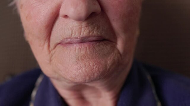 Extreme close-up of an elderly woman's mouth showing genuine emotions and a sense of closeness. Wrinkles on her mature skin move as she smiles, revealing the beauty and wisdom of aging gracefully