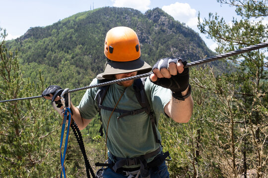 Person Climbs Mountain Using Cable 