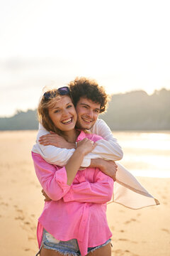 Happy couple hugging on beach during vacation sunset
