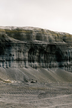 A volcanic cliff in Lanzarote with layers of dark ash and sediment.
