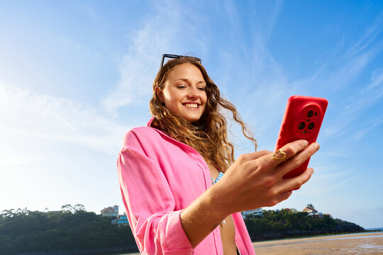 Young woman enjoying beach vacation using smartphone