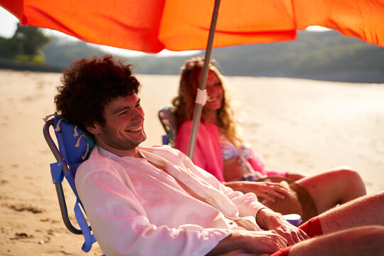 Happy couple relaxing on beach chairs under umbrella