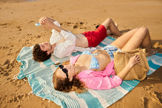 Young couple relaxing on beach creating summer vacation memories