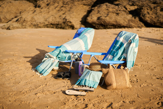 Beach chairs on sand with towels, hat, bag for vacation