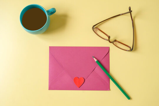 Pink paper envelope with mini heart sign on a color background.