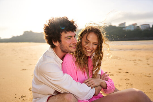 Happy couple hugging on beach during golden hour