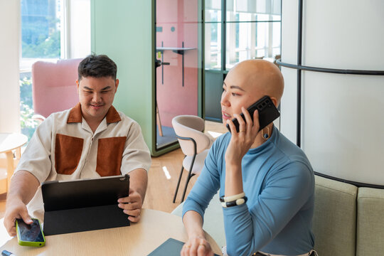 Two Colleagues Work on Devices in a Bright Office Setting