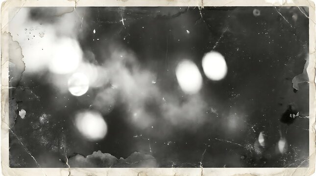 Vintage black and white abstract photographic image depicting blurry bokeh lights and ethereal smokelike textures with distressed antique paper edges creating a dreamy atmospheric mood.
