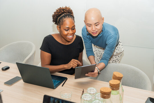 Two Women Working Together on a Tablet in a Meeting Room