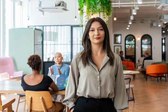Woman Standing in a Modern Workspace During a Casual Meeting