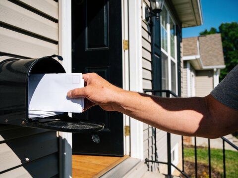 Person Checking Mailbox on Front Porch