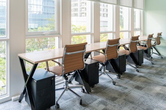 Office Workspace With Several Chairs and Desks by Large Windows
