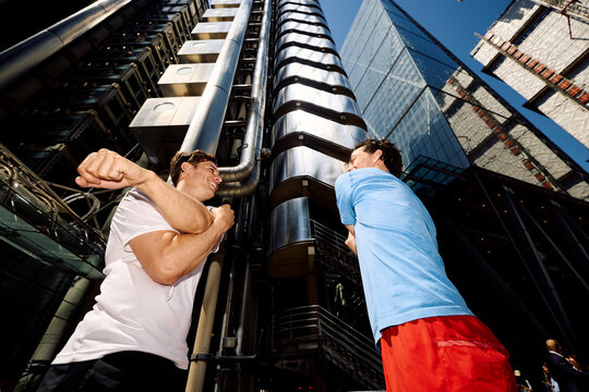 Active men warm up themselves in front of tall buildings