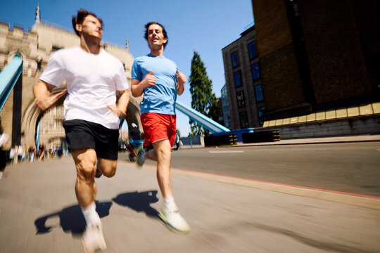 Two men jogging across Tower Bridge in London