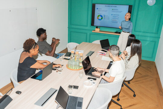 Team Members Discuss Ideas in a Meeting Room With a Presentation