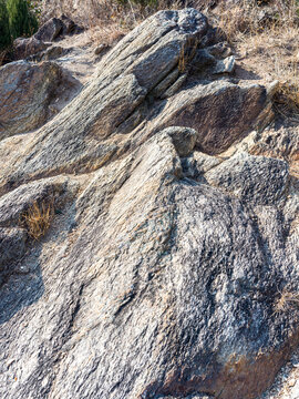 Angled layers of gray schist rock formation illuminated by bright sunlight