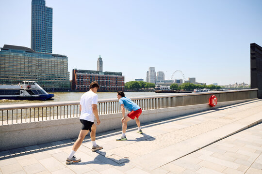 Two men exercise outdoors by the Thames River