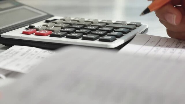사무실에서 계산기를 두드리며 영수증을 확인하고 정산 업무를 하는 모습입니다.