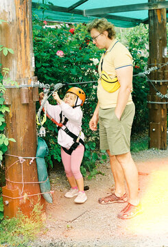 Child Climbs at Adventure Park While Adult Watches Closely