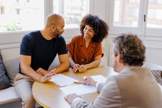 Couple consulting financial advisor discussing important documents