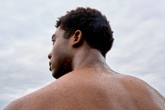 Person Stands Outdoors With Wet Skin Looking Towards the Sky