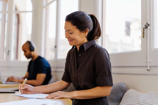 Brunette woman writing notes while working in bright office