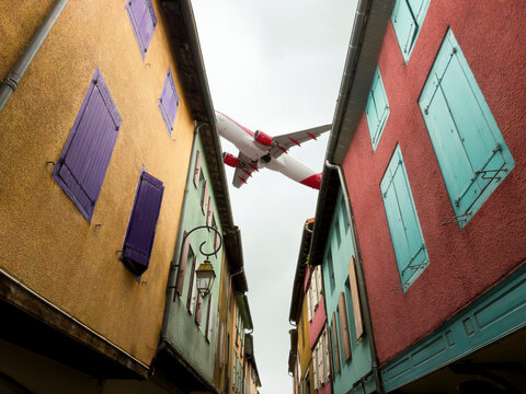 Airplane Flying Low Over Colorful Old Town Alley