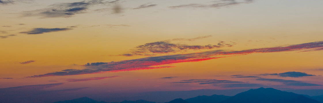 Panoramic Sunset Sky with Vibrant Pink and Orange Clouds Over Mountain