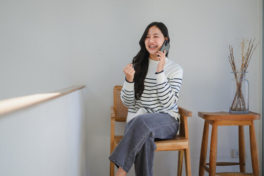 Happy young woman talking on phone celebrating good news