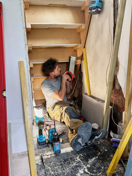 DIY Carpenter Installing Understairs Storage During Home Renovation