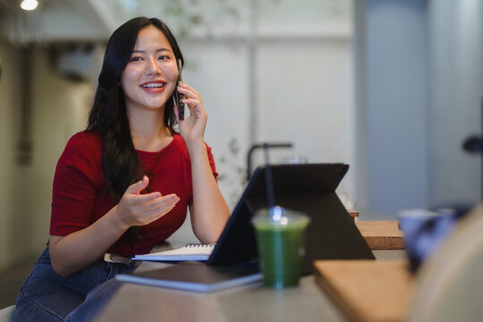 Smiling woman talking on phone working in cafe