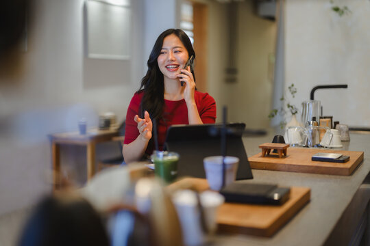 Young Asian woman talking on smartphone in cafe