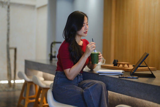 Young woman enjoying healthy drink at modern cafe counter