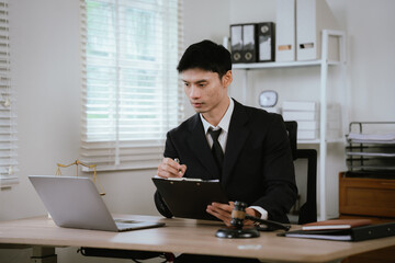 Fototapeta premium Thoughtful lawyer working on a laptop in a modern office with a judge's gavel, representing legal research, strategy, and decision-making.